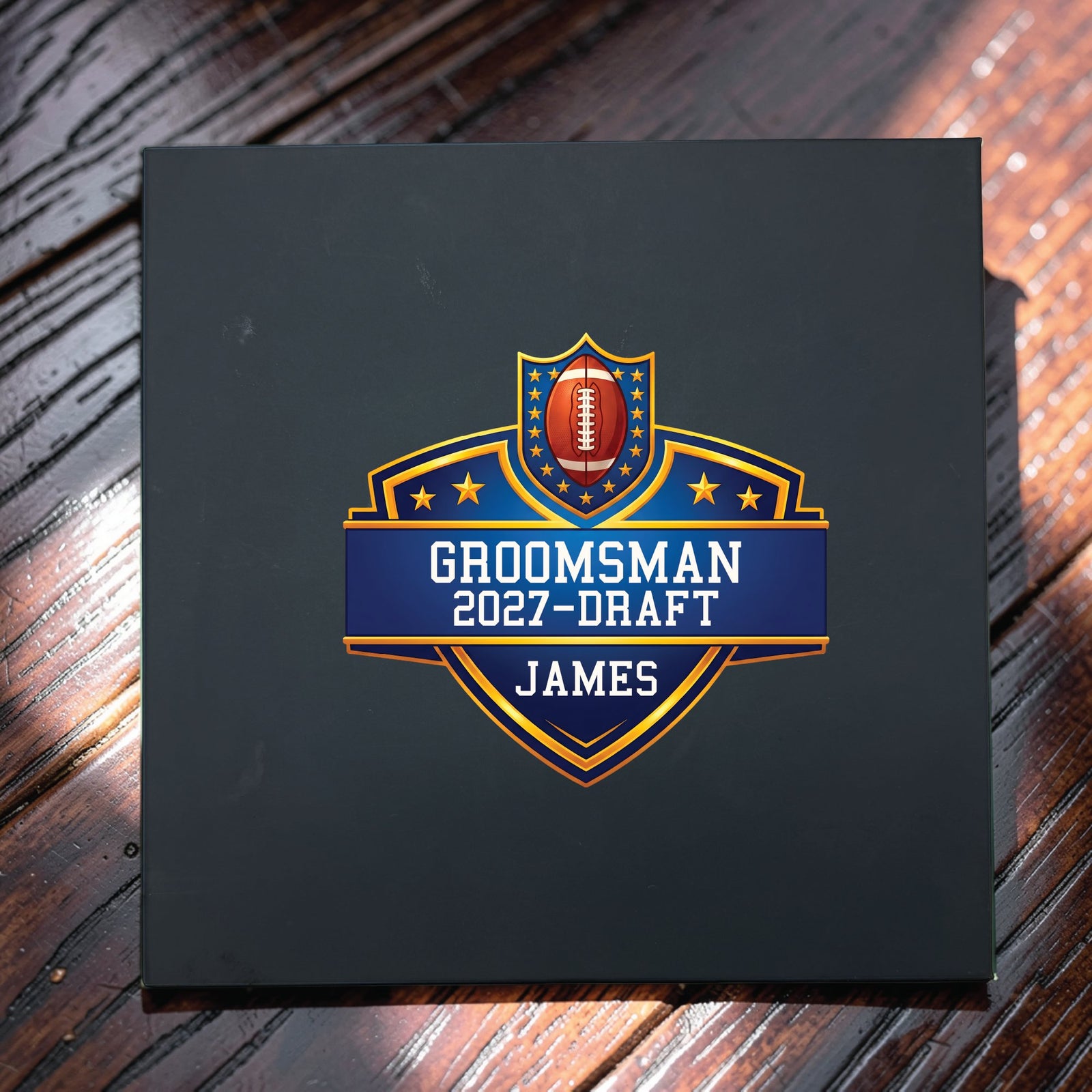 Closed black groomsmen proposal gift box with the football draft shield UV printed in full colour, showing the wedding role, the 2027 draft year and the name James.