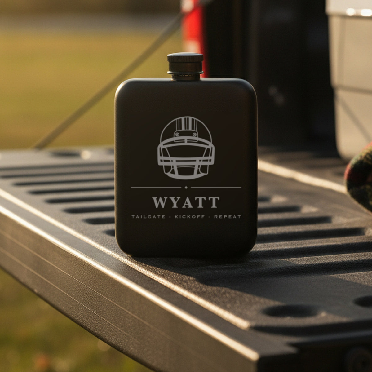 Personalized football flask engraved Tailgate Kickoff Repeat standing on the steel tailgate of a pickup truck on an autumn afternoon.