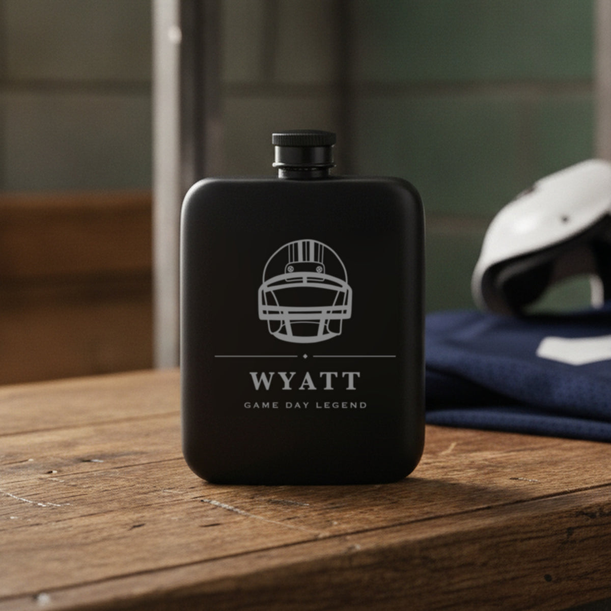 Engraved football groomsmen flask reading Game Day Legend standing on a worn wooden locker room bench with stall dividers behind.