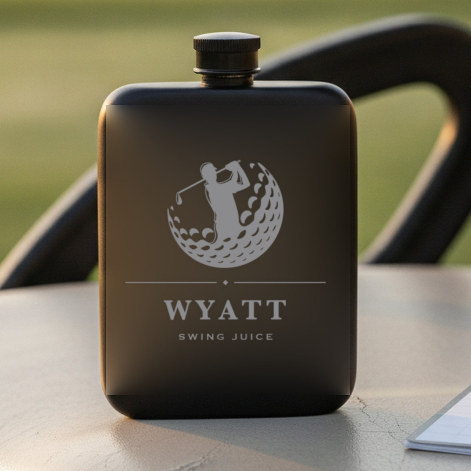 Personalized golf groomsmen flask reading Swing Juice on a golf cart seat beside a scorecard with a sunlit fairway behind.