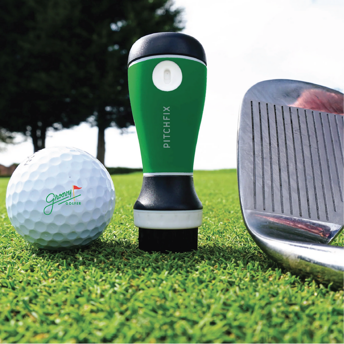 Green AquaBrush golf club cleaner from the groomsman golf gift set, standing on the green beside a branded golf ball and an iron.