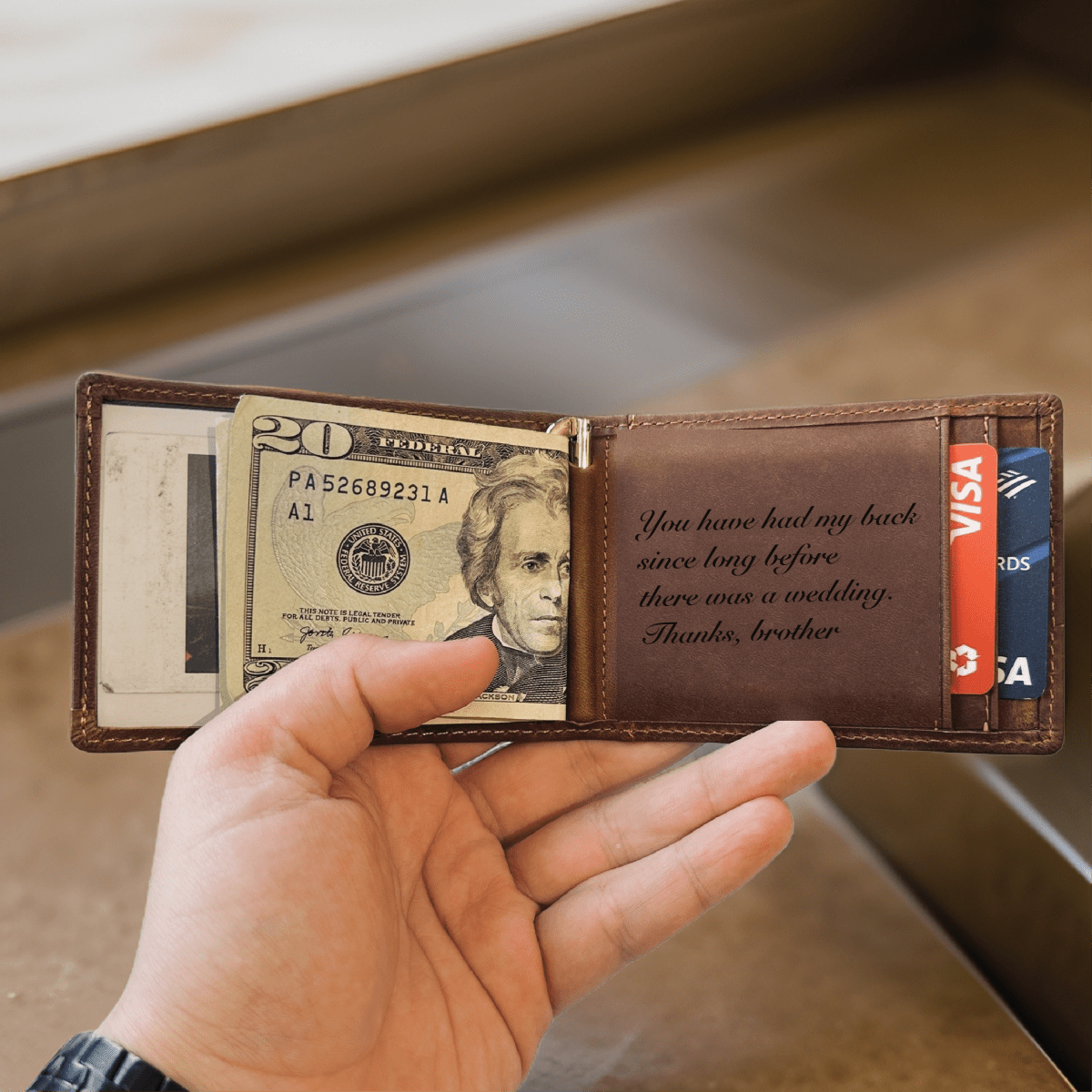 Personalized leather wallet held open showing a groomsman thank-you message laser-engraved inside the brown leather panel in script.