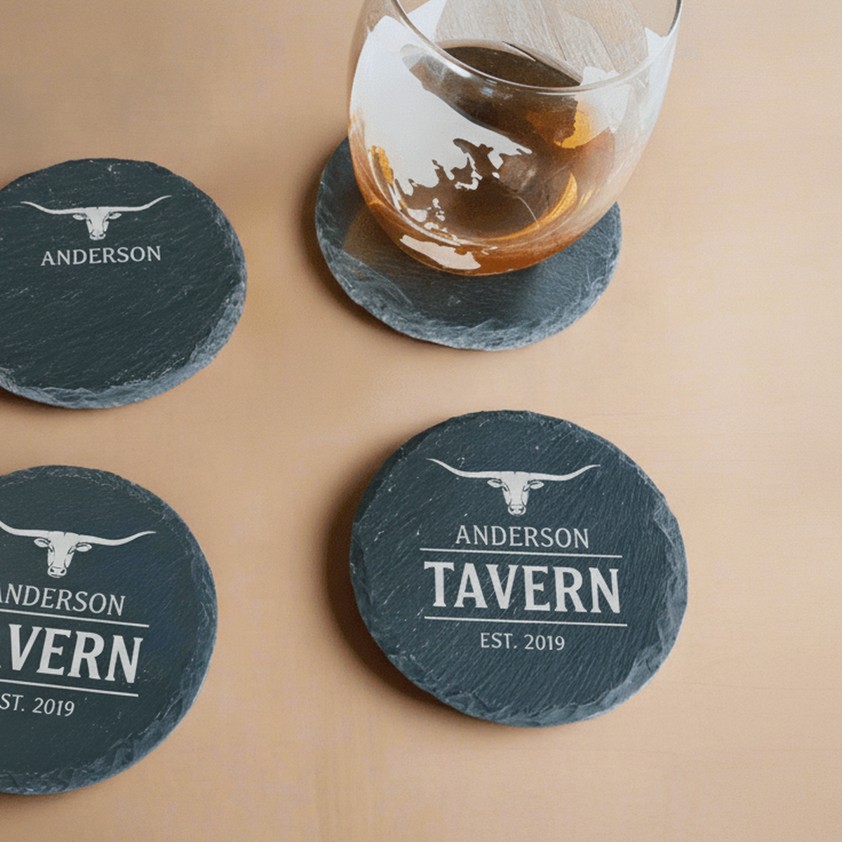 Personalized slate coasters engraved with a longhorn emblem, last name, and a big word like Tavern, styled as a home bar set with a whiskey glass