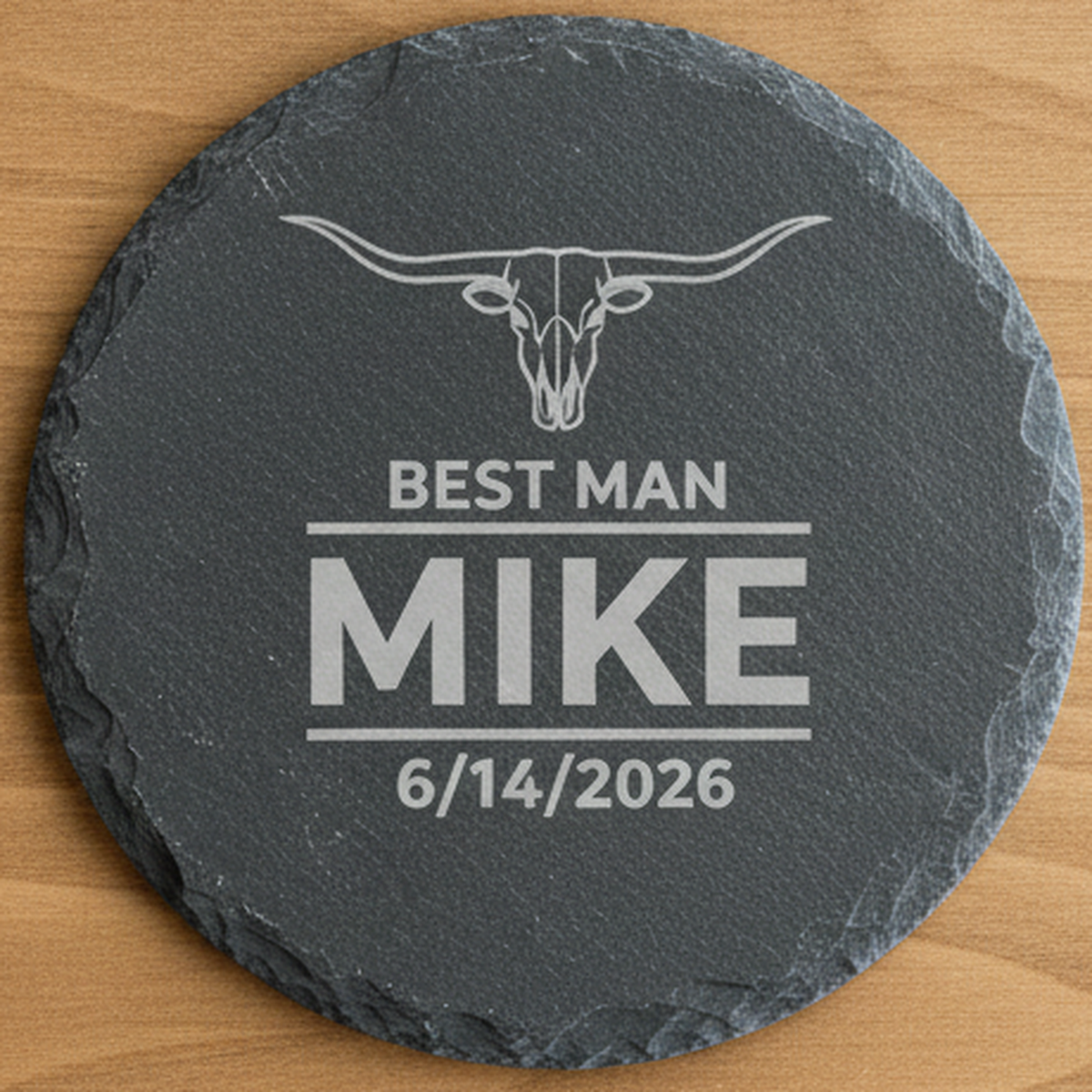 Close detail of a single personalized slate coaster engraved with a longhorn emblem, wedding role, first name, and wedding date
