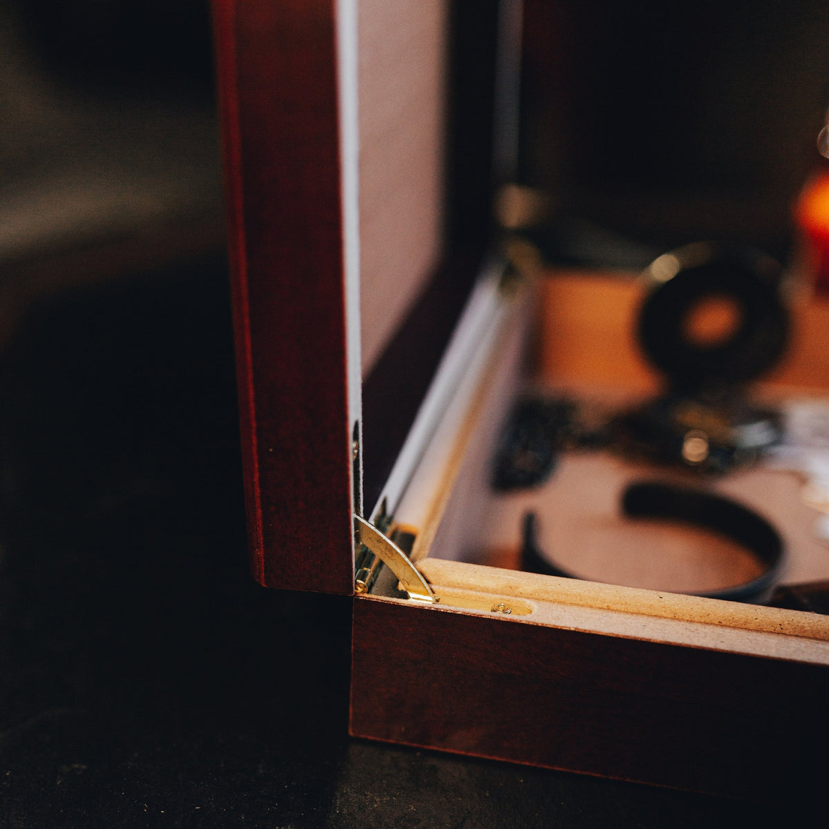 Brass locking hinge and the open lid of the personalized groomsmen keepsake box, photographed close up in warm low light.