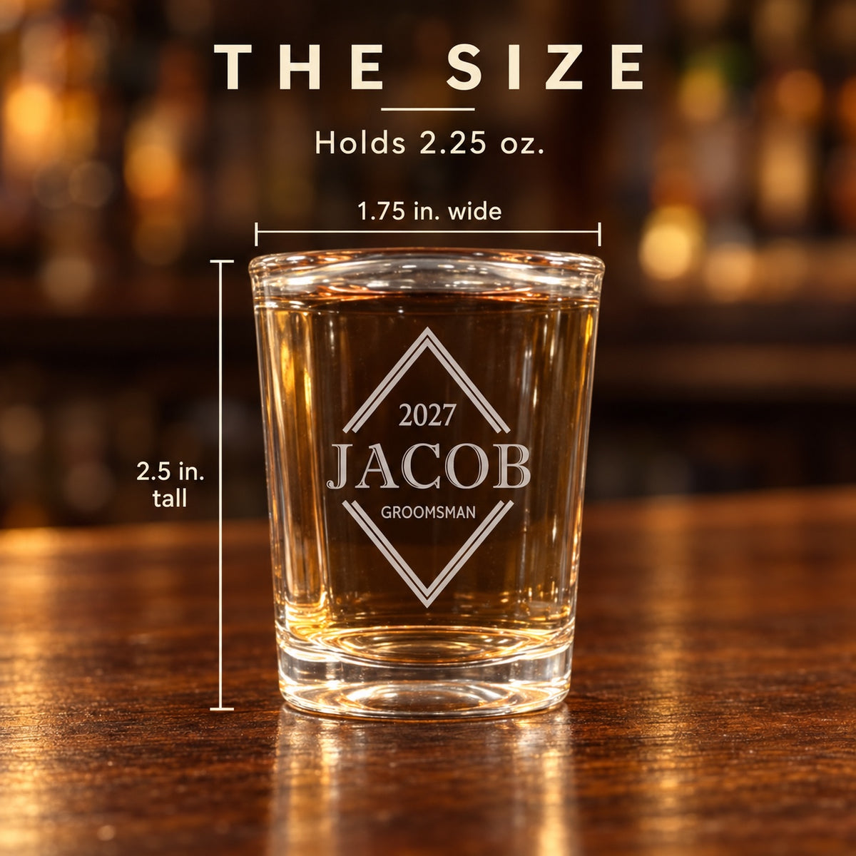 Size card for an engraved groomsmen shot glass, 2.5 inches tall and 1.75 inches wide at the rim, holding 2.25 ounces, shown on a wood bar top.