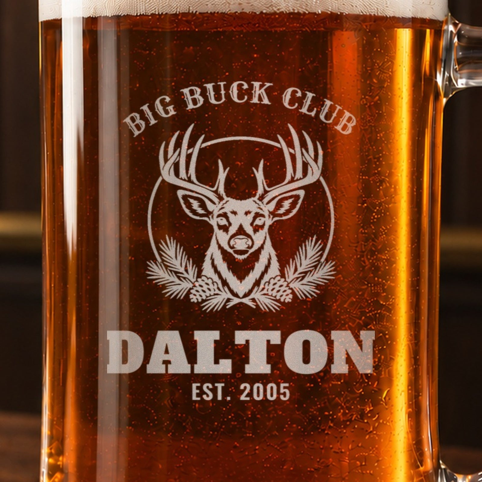 Close-up of the frosted engraving on the hunting camp beer stein, a whitetail buck and pine boughs: Big Buck Club, Dalton, Est. 2005