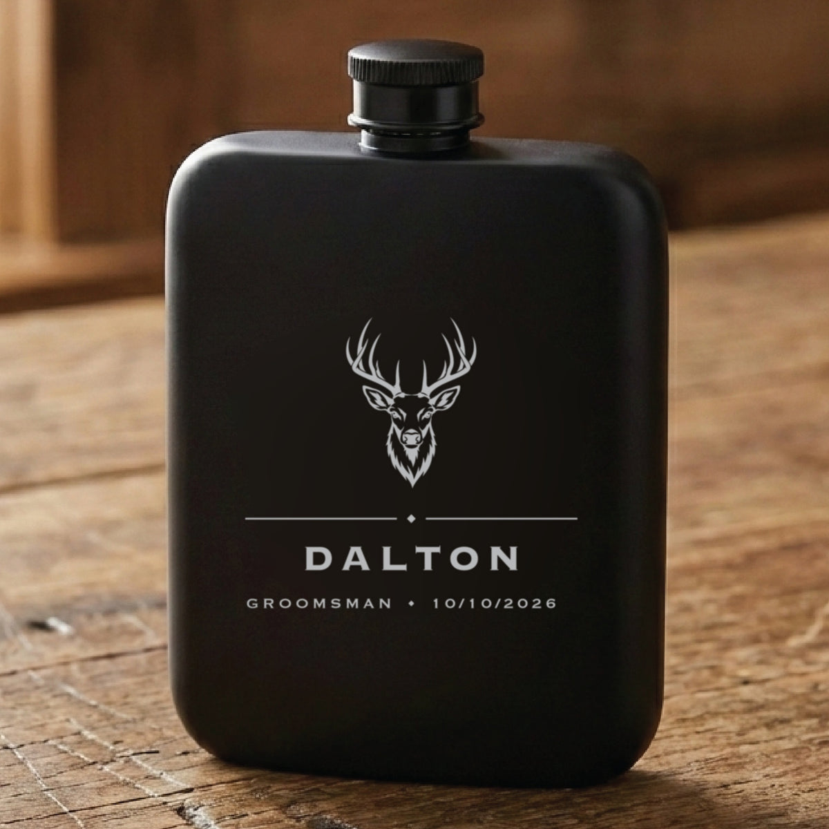 Matte black hunting groomsmen flask laser engraved with a whitetail buck above the name Dalton, his role and the wedding date.