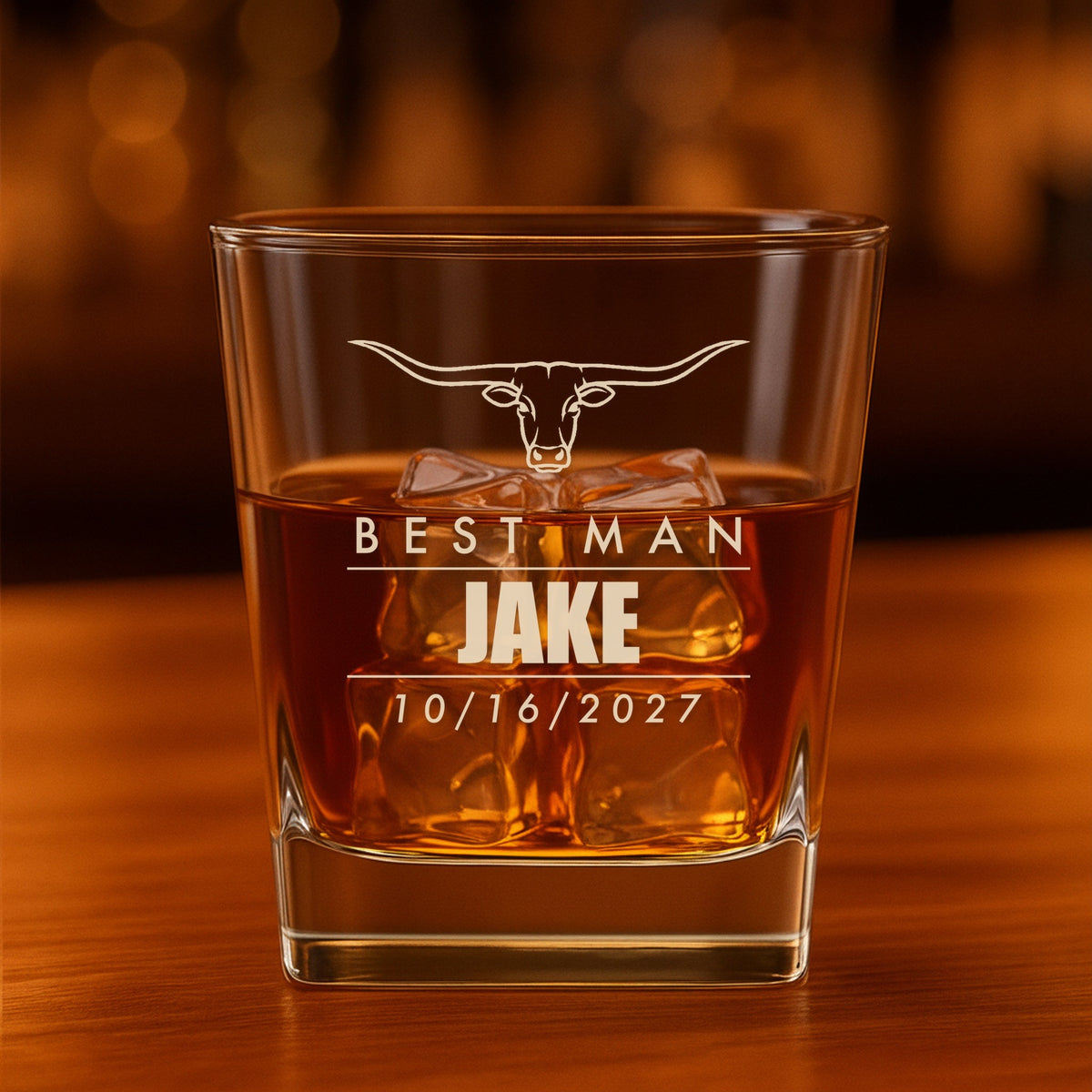 Personalized groomsmen whiskey glass engraved with a longhorn steer, Best Man, Jake and the wedding date 10/16/2027, filled with bourbon