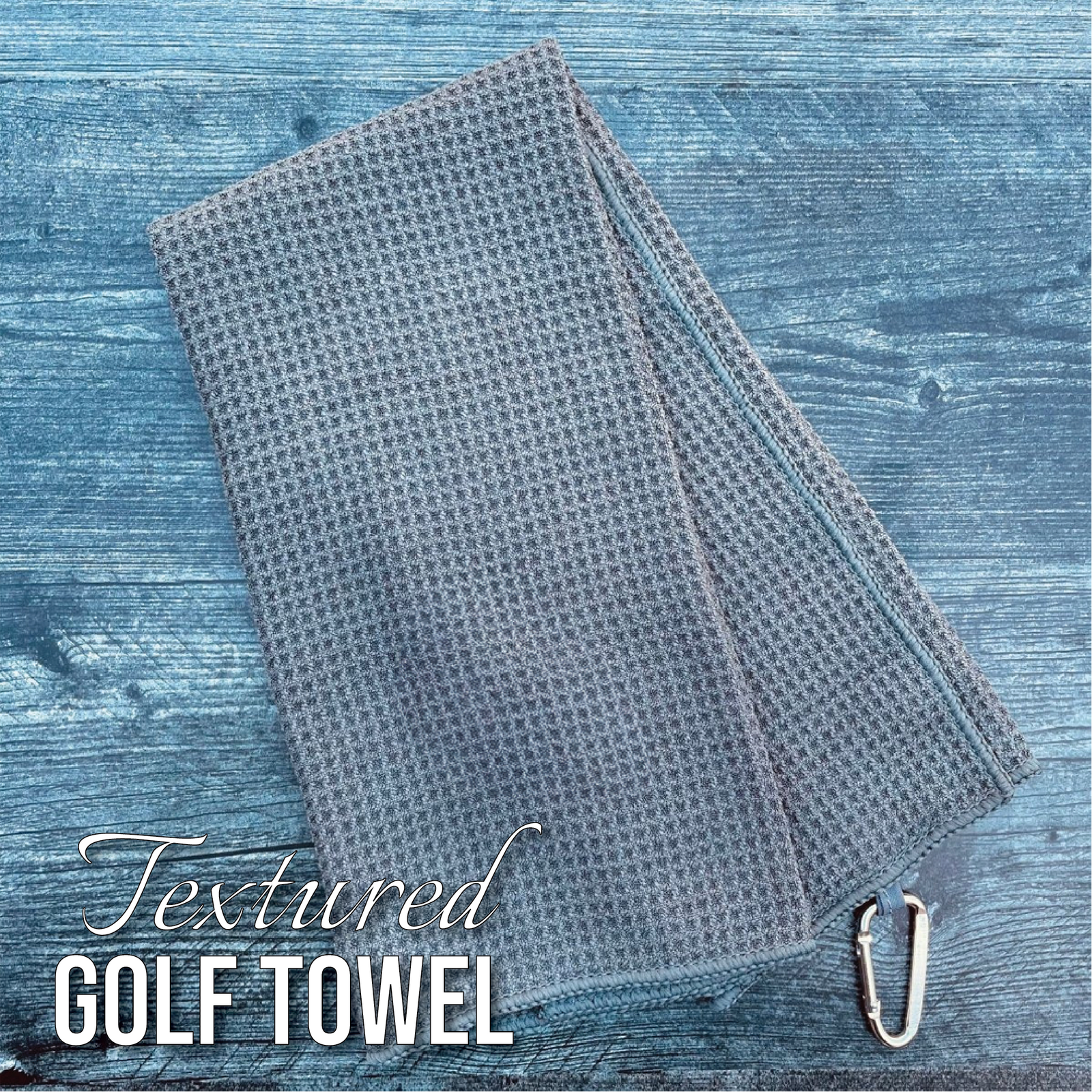 Gray textured golf towel with grommet, displayed folded on blue wooden surface
