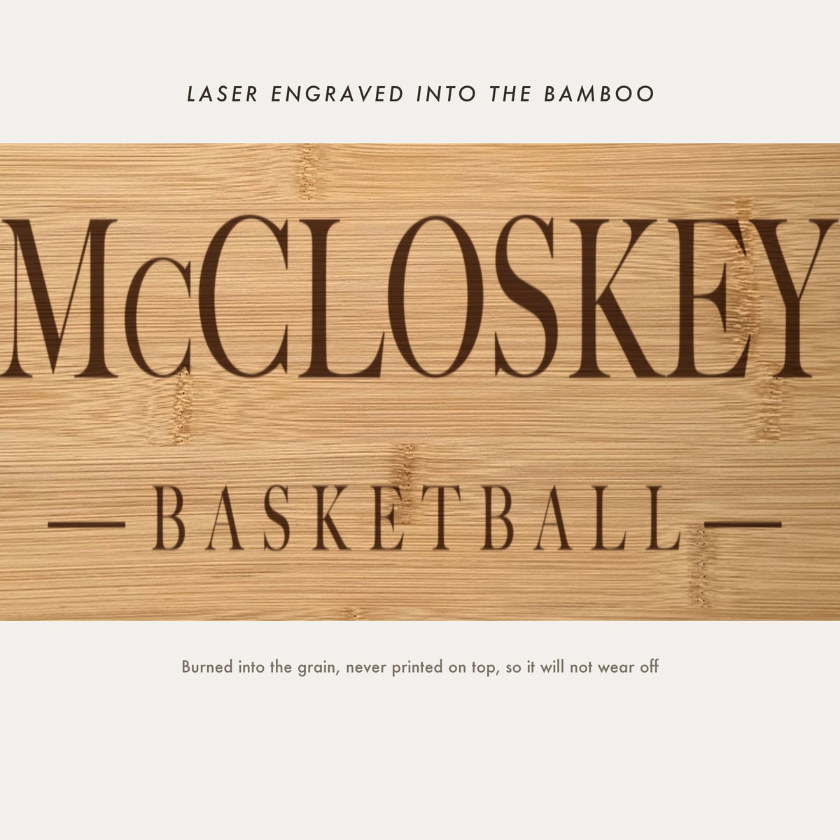 Close view of the family name and the word Basketball laser engraved into the bamboo grain in spaced serif capitals between two fine rules.