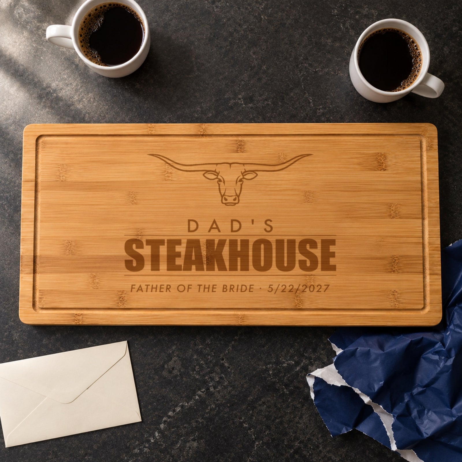 Father of the bride gift from the bride: a steakhouse cutting board engraved DAD'S STEAKHOUSE, FATHER OF THE BRIDE 5/22/2027, just unwrapped from navy paper