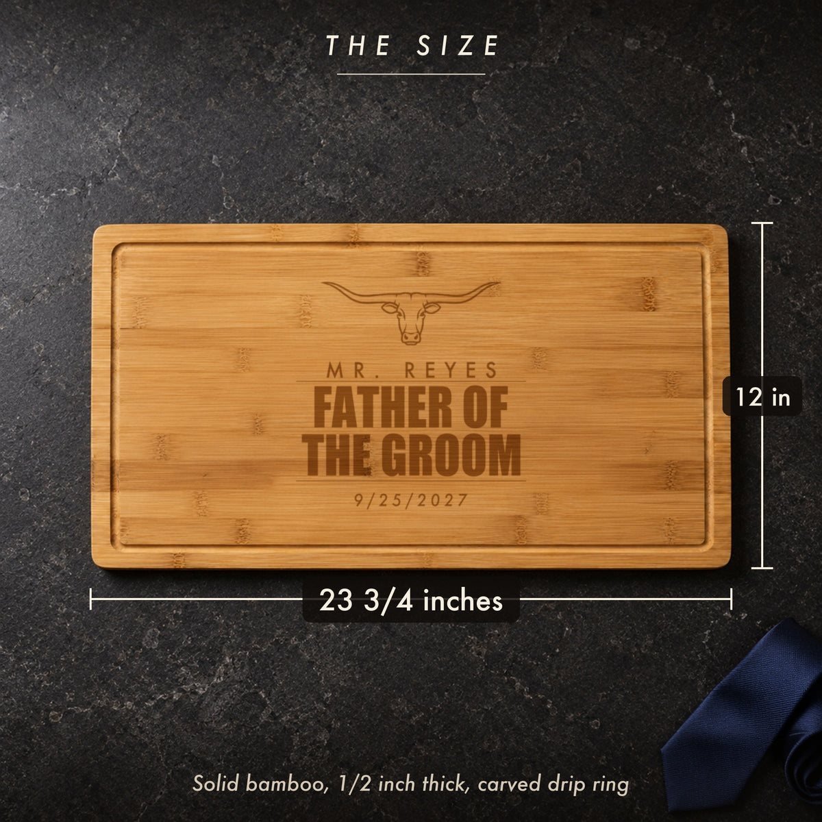 Size of the father of the groom cutting board, 23 3/4 inches long by 12 inches wide in half inch solid bamboo, on a dark stone counter with a navy tie