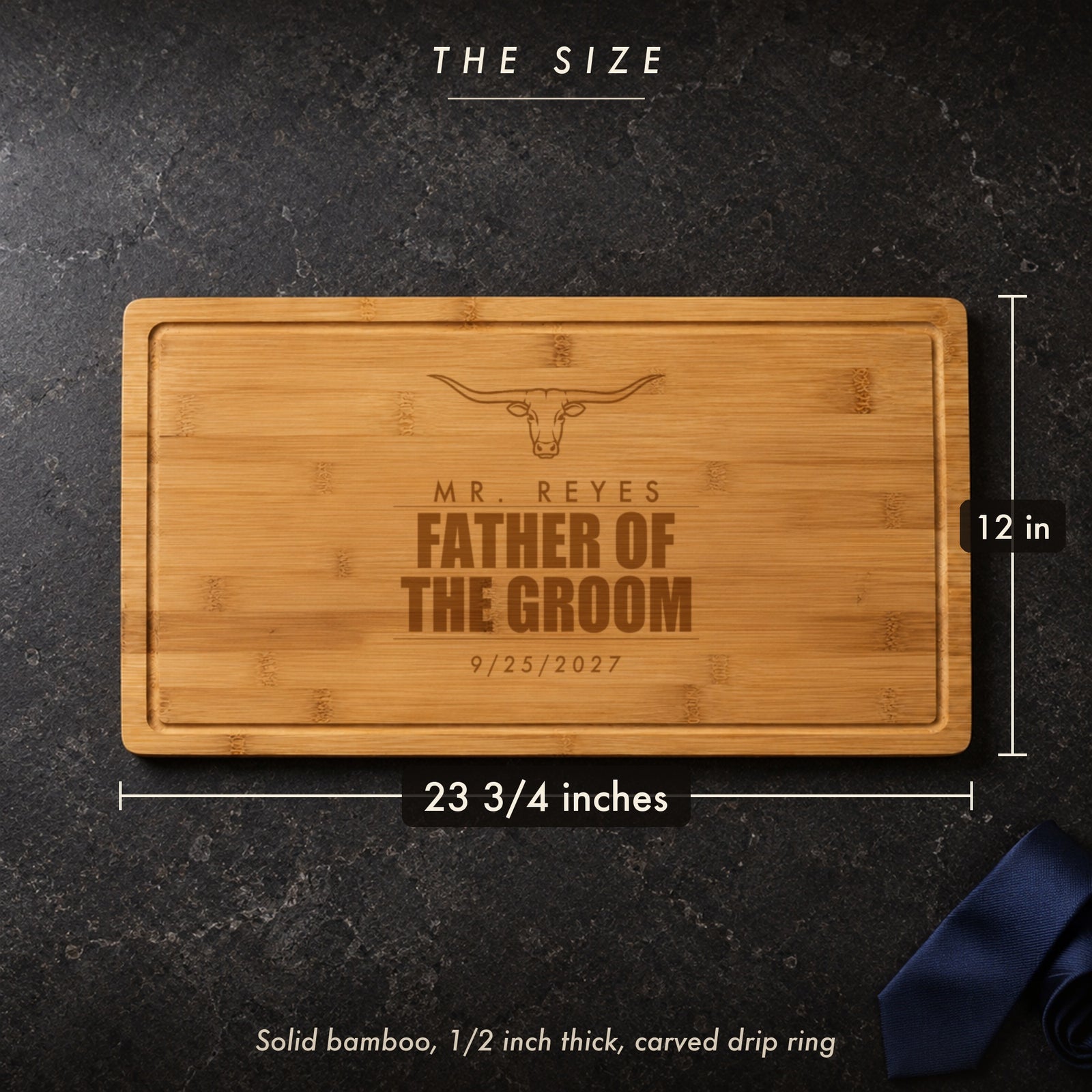 Size of the father of the groom cutting board, 23 3/4 inches long by 12 inches wide in half inch solid bamboo, on a dark stone counter with a navy tie