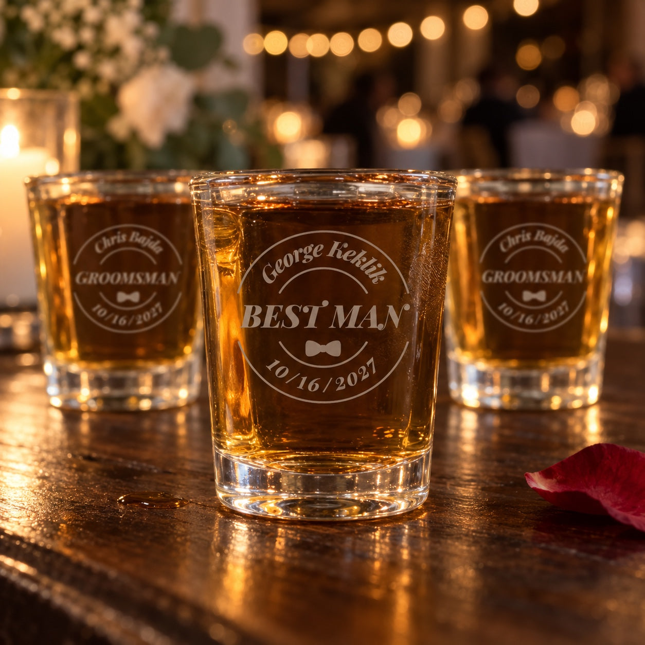 Personalized groomsmen shot glasses on a reception bar, the front glass engraved George Keklik, Best Man and 10/16/2027 in a round badge