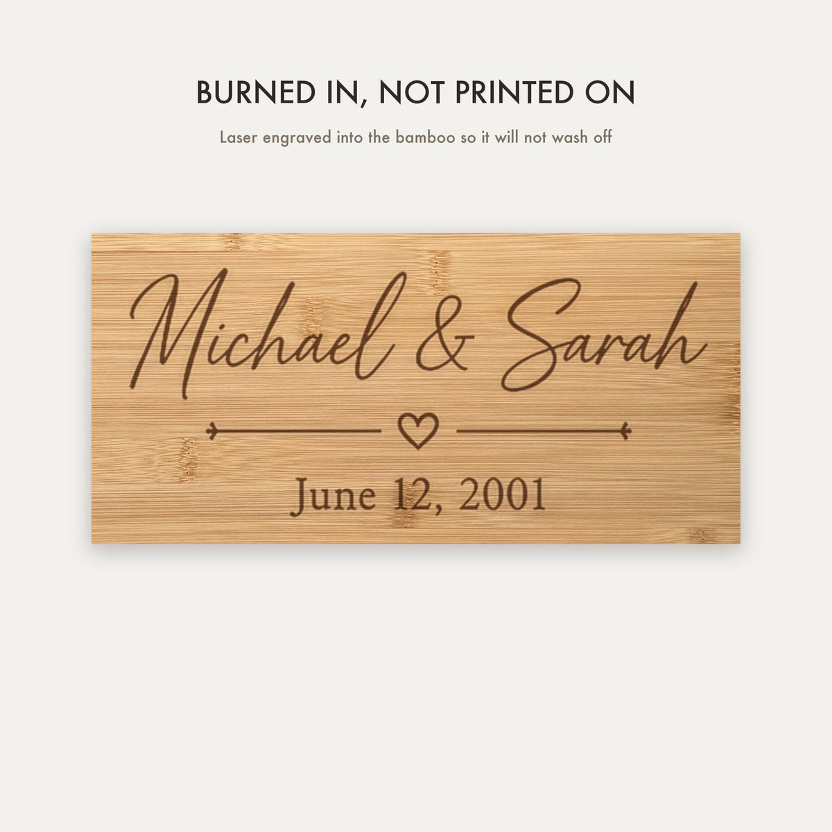 Close view of the laser engraving burned into the bamboo grain showing the couple's names, the heart divider and the wedding date.