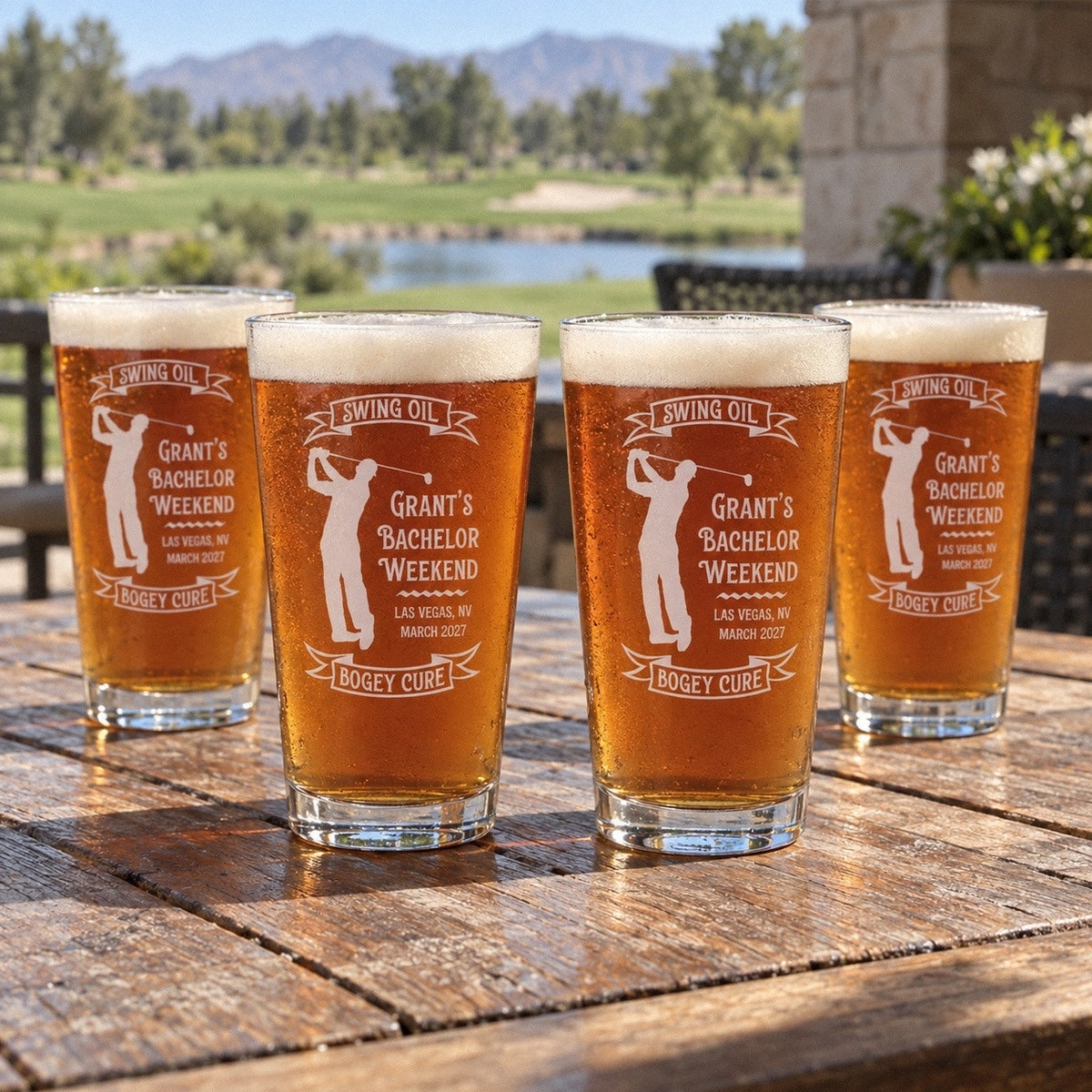 Four golf bachelor weekend pint glasses on a clubhouse patio table, each reading Swing Oil, GRANT'S BACHELOR WEEKEND, LAS VEGAS, NV, MARCH 2027