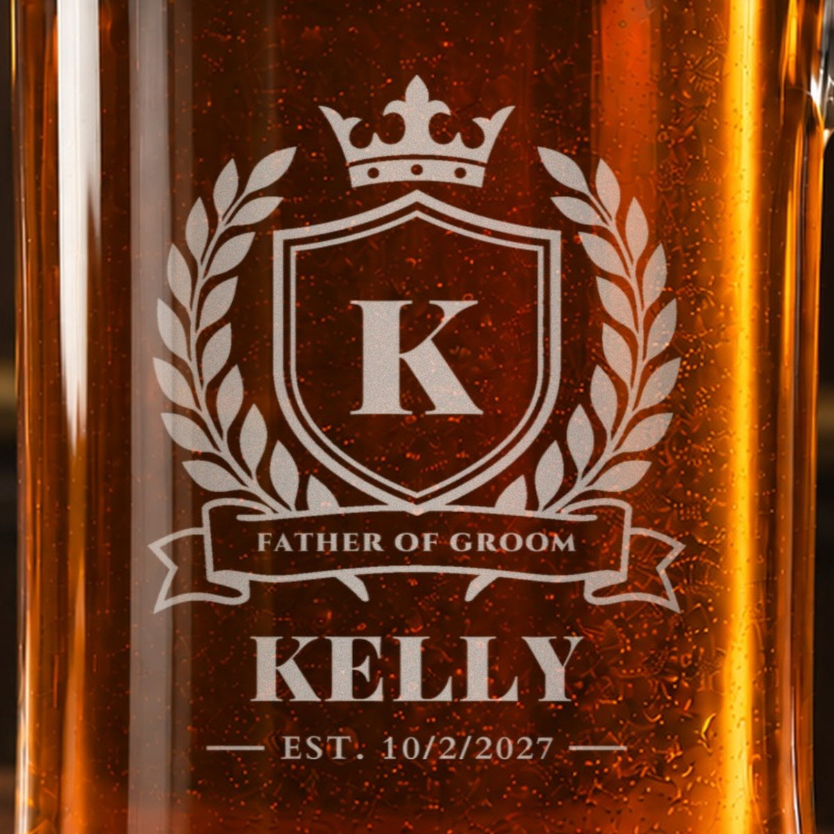 Close-up of the frosted crest engraving on a groomsmen beer stein: a crown and laurel, the initial K, Father of Groom, Kelly and Est. 10/2/2027