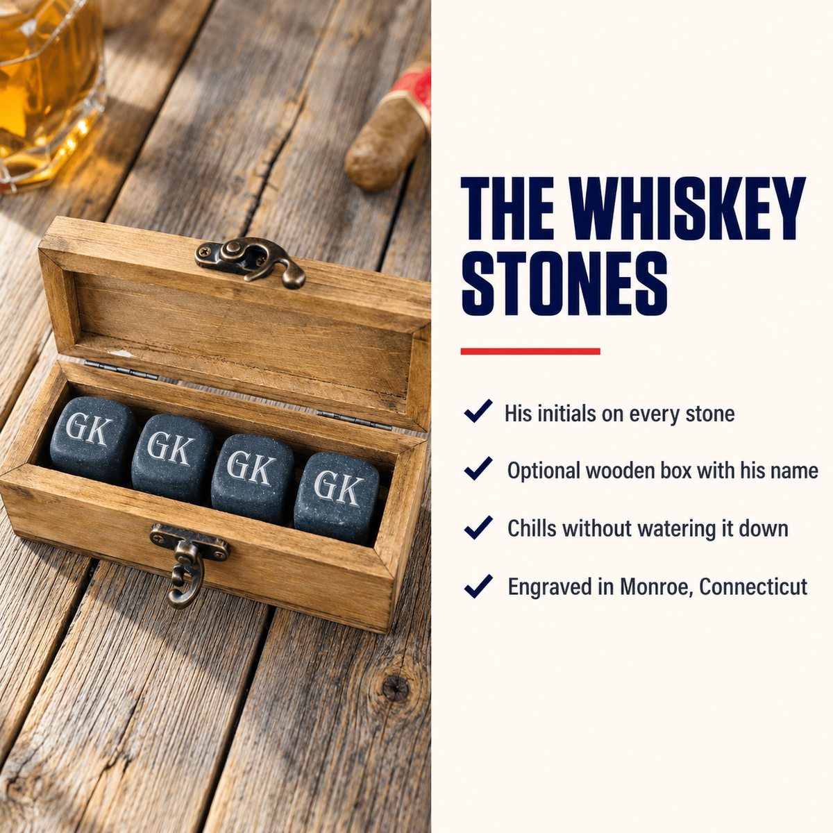 Wooden box containing four engraved black whiskey stones with "GK" initials, displayed open on a wood surface with a glass of whiskey.
